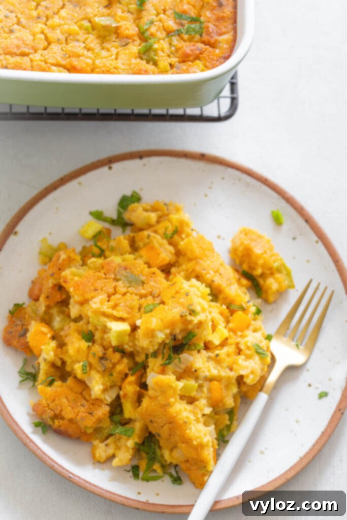 A beautifully plated serving of Southern Squash Dressing with a fork, emphasizing its tender texture and golden-brown crust.