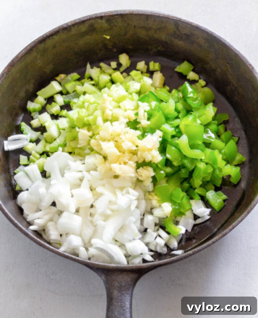 Close-up of chopped celery, garlic, onions, and green peppers sizzling in a hot cast iron skillet, cooking to perfection for the dressing.