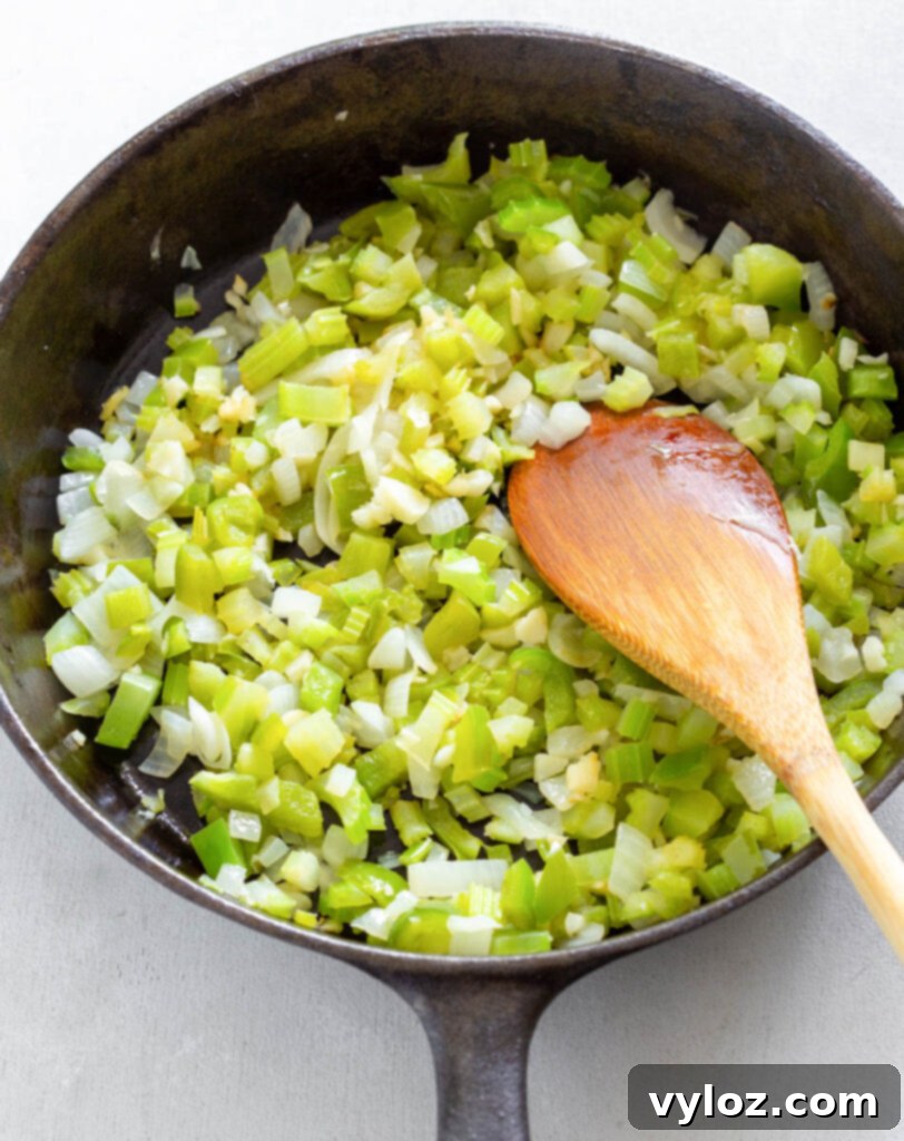 Another view of chopped celery, garlic, onions, and green peppers continuing to sauté in a cast iron skillet, releasing their aromatic flavors.