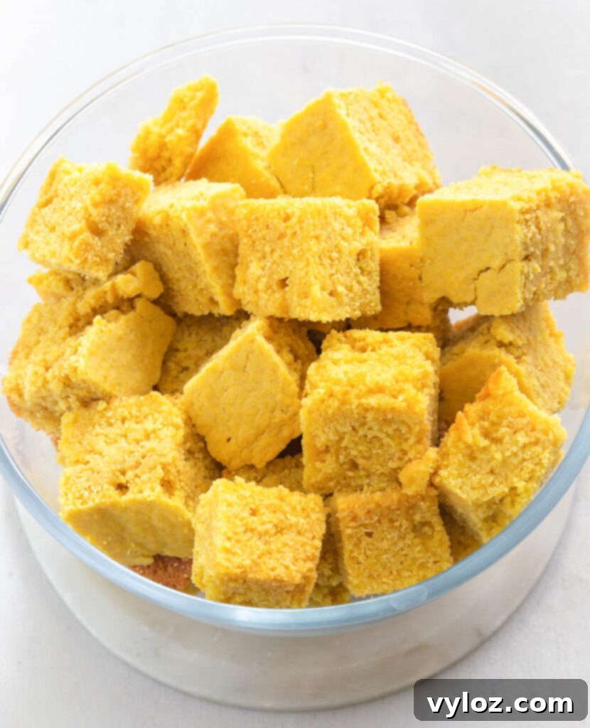 Day-old cornbread, neatly cut into cubes and placed in a bowl, ready to be crumbled for the dressing mixture.