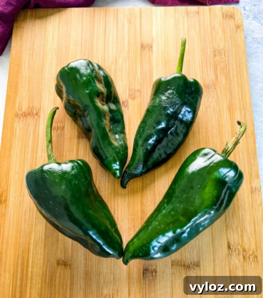4 poblano peppers on a wood cutting board