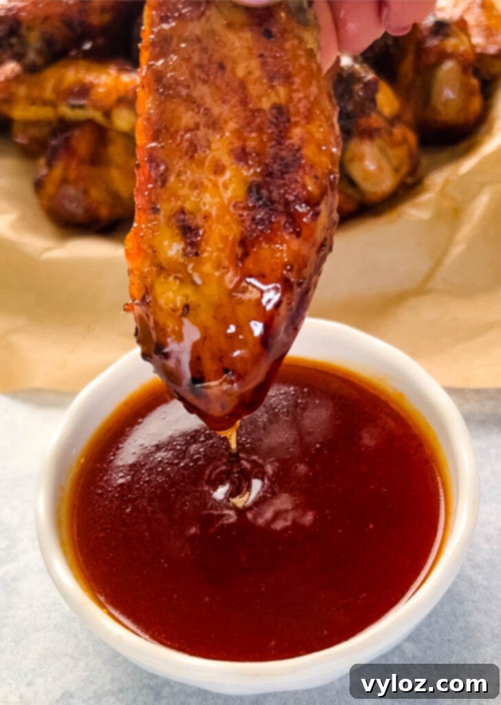 Fiery Honey Glazed Wings 2 person holding honey hot wing with hot sauce