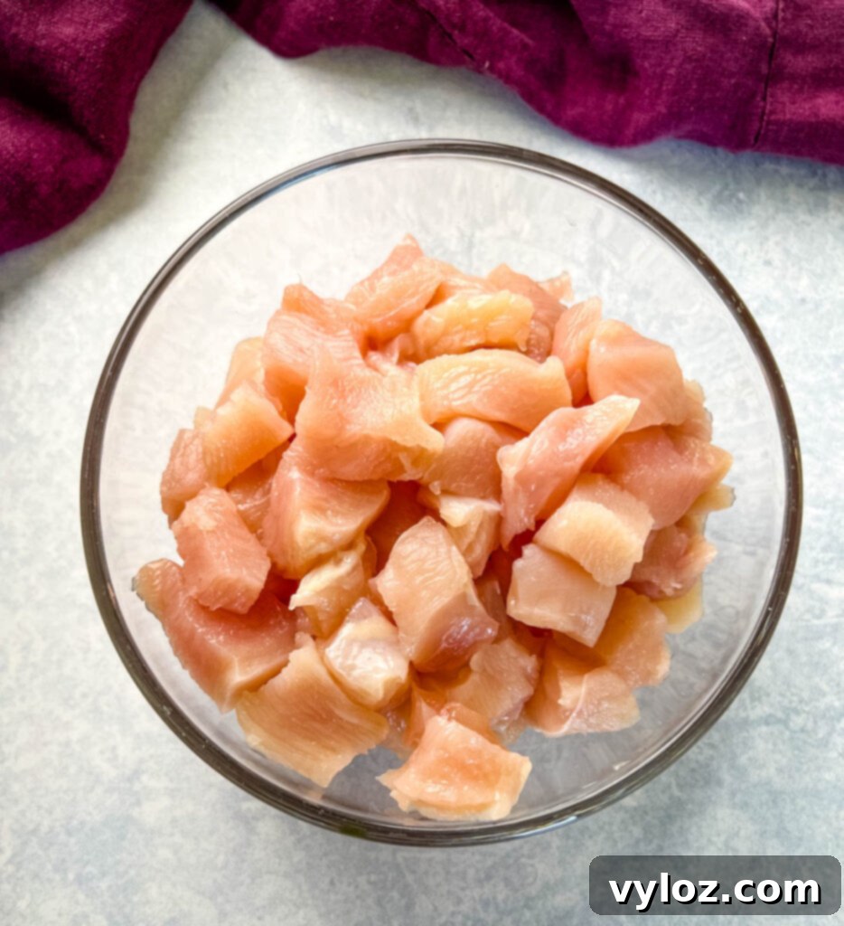 raw and cubed chicken breasts in a glass bowl