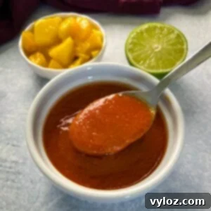 A bowl of homemade mango habanero sauce with a spoon, ready for serving.