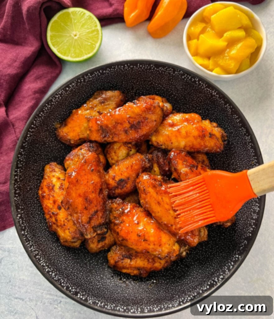 A bowl of perfectly glazed mango habanero wings, brushed with sweet and spicy sauce.