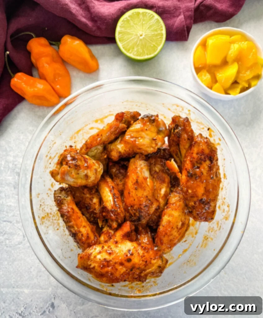 Raw chicken wings seasoned and ready for cooking in a glass bowl.