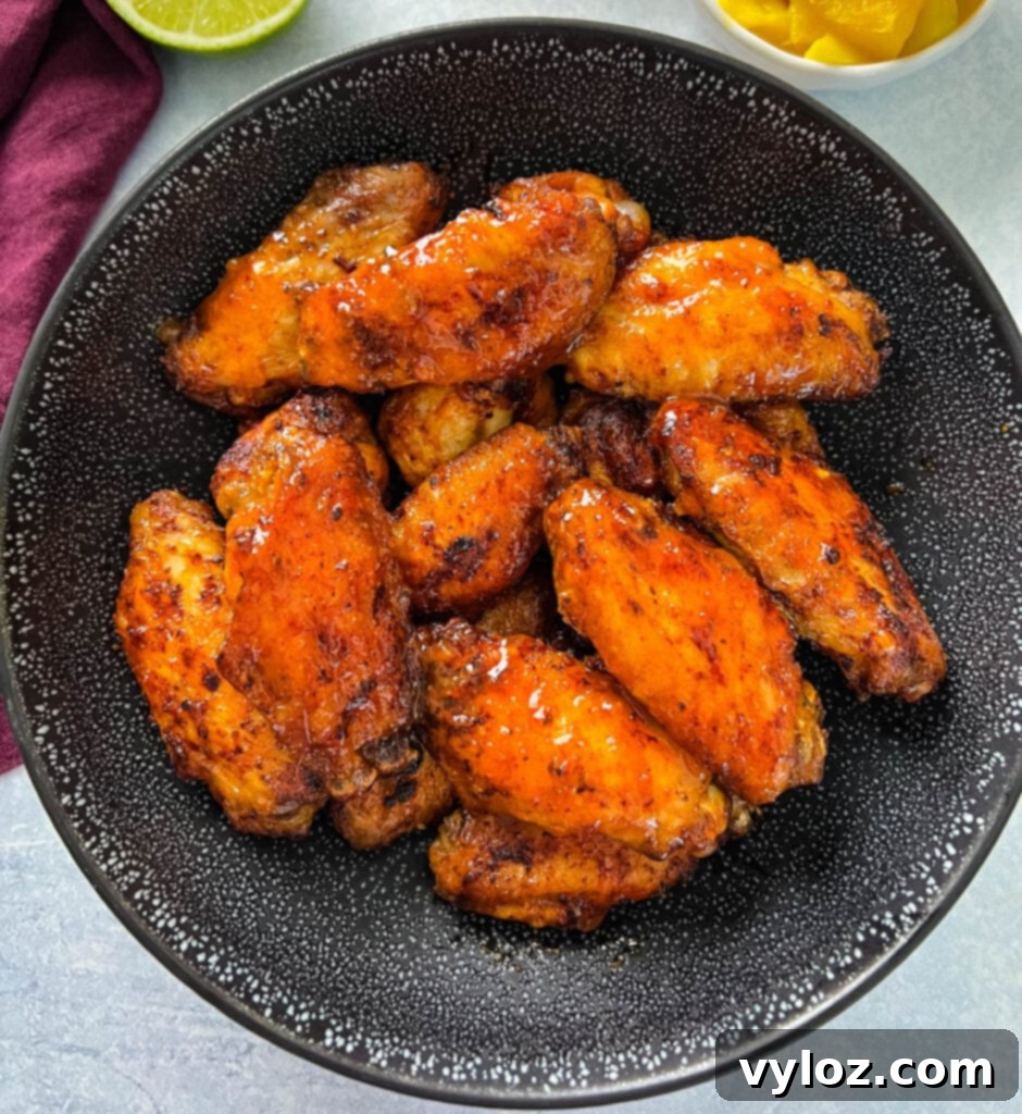 A black bowl filled with freshly cooked mango habanero wings.