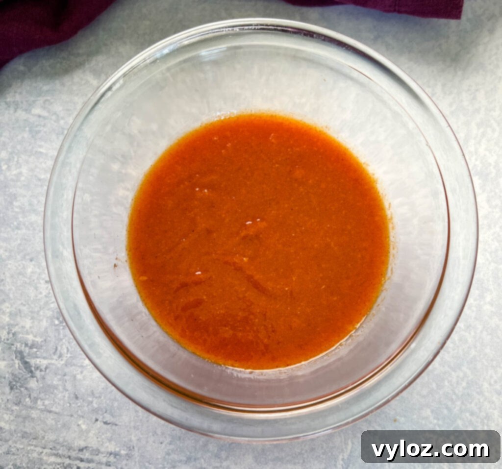 A glass bowl showcasing the vibrant orange of homemade mango habanero sauce.