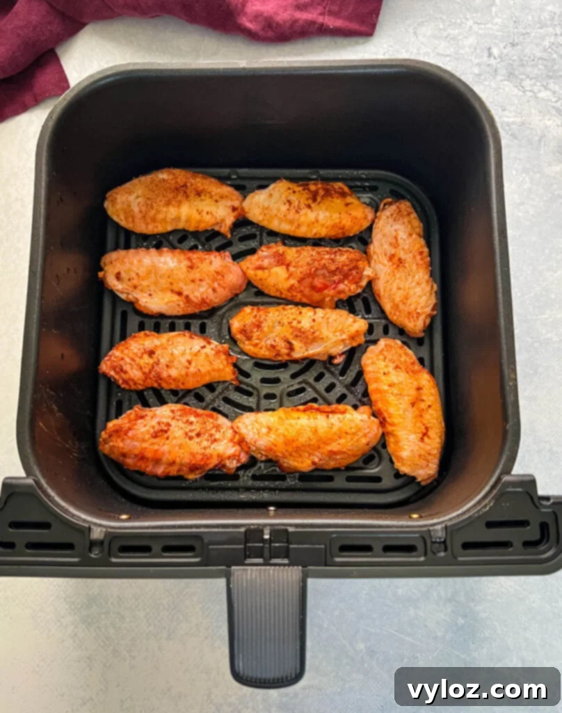 Raw seasoned chicken wings arranged in an air fryer basket.