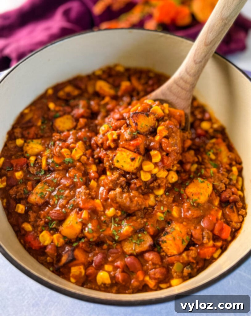 Hearty Butternut Squash Chili with Your Choice of Meat 11 A large wooden spoon scooping butternut squash chili from a bowl.