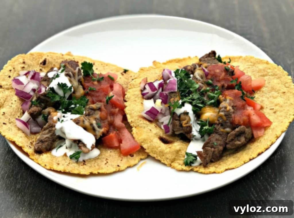 10-Minute Instant Pot Carne Asada Tacos 2 Delicious Instant Pot 10-Minute Steak Tacos with salsa, cilantro, and sour cream on a white plate