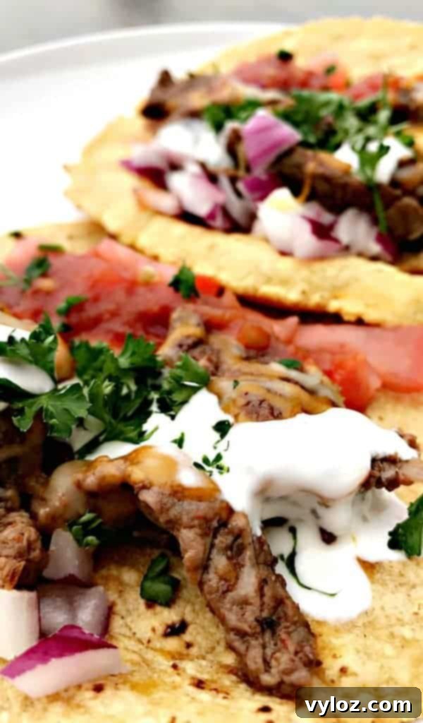 10-Minute Instant Pot Carne Asada Tacos 4 Close-up of Instant Pot 10-Minute Steak Tacos (Carne Asada) garnished with sour cream and fresh tomatoes
