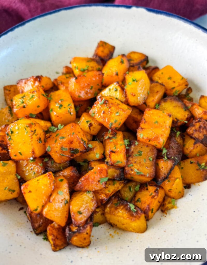 Close-up of air fryer butternut squash in a white bowl, garnished with herbs