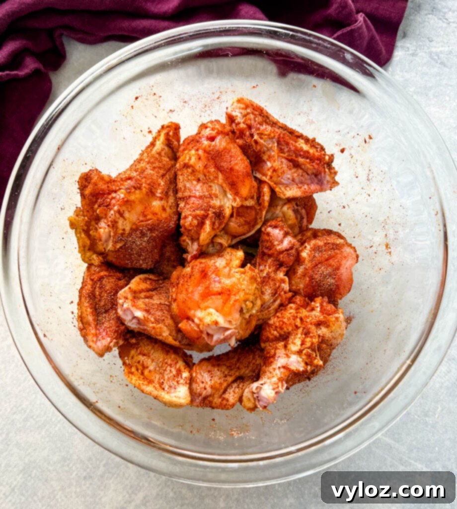 raw chicken wings seasoned in Cajun rub in a glass bowl