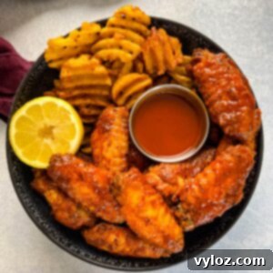 hot lemon pepper chicken wings in a black bowl with fresh lemon and hot sauce