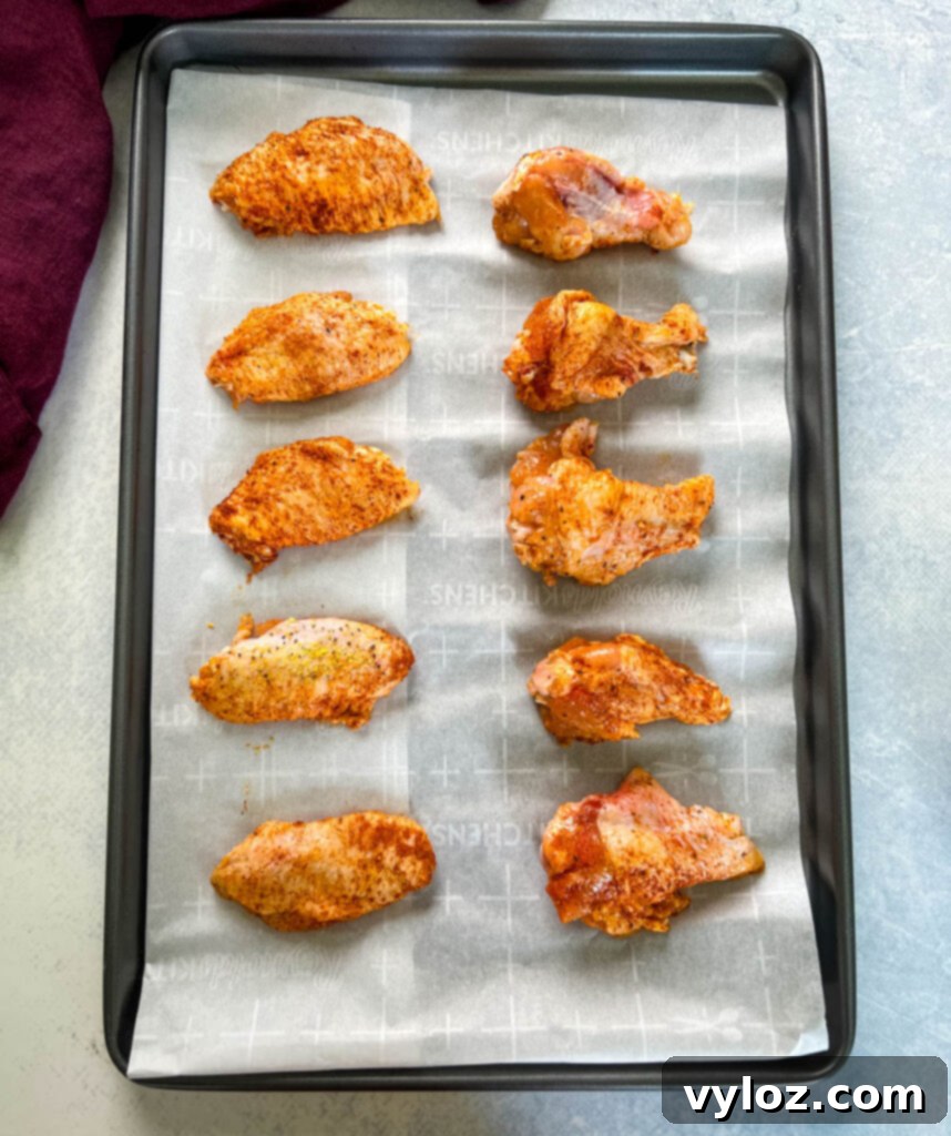 raw hot lemon pepper chicken wings on a sheet pan with parchment paper