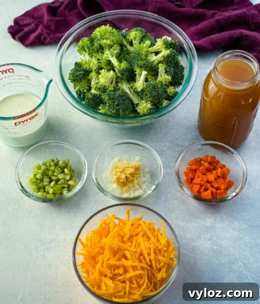 Creamy Slow Cooker Broccoli Cheddar Soup 3 Glass bowls filled with ingredients for broccoli cheddar soup including fresh broccoli florets, shredded cheddar cheese, diced carrots, celery, onions with garlic, a measuring cup of cream, and a jar of broth.