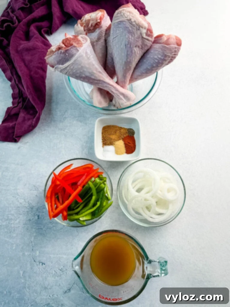 Raw turkey legs in a glass bowl surrounded by bowls of sliced red and green bell peppers, onions, a small dish of seasoning spices, and a measuring cup of broth. Everything is arranged neatly on a light surface with a purple linen in the corner.