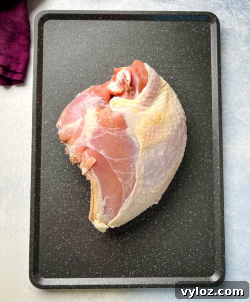 Raw bone-in turkey breast, perfectly prepped on a sheet pan, awaiting its flavorful seasoning