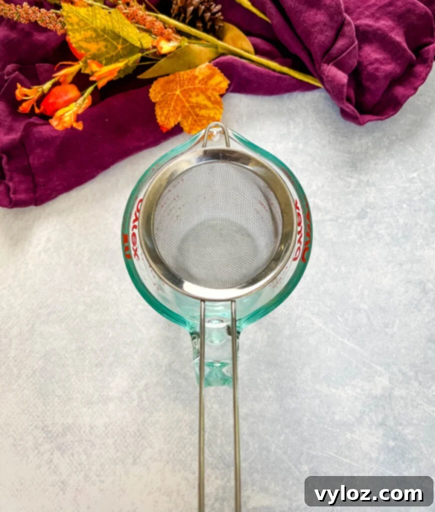 Caramel Apple Bliss 7 A mesh strainer placed over a clear glass bowl, ready for straining apple cider