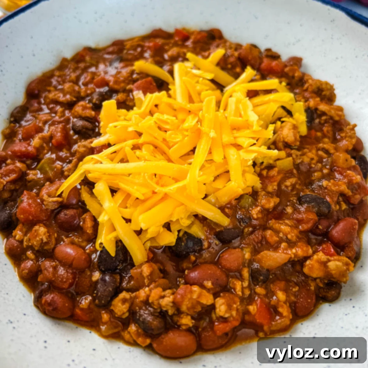 Hearty Ground Chicken Chili 2 A bowl of delicious ground chicken chili, topped with shredded cheese, ready to be enjoyed.