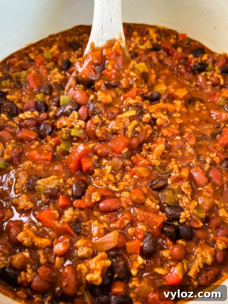 Hearty Ground Chicken Chili 12 A close-up shot of ground chicken chili with beans and a rich sauce, served in a Dutch oven, garnished with cilantro.