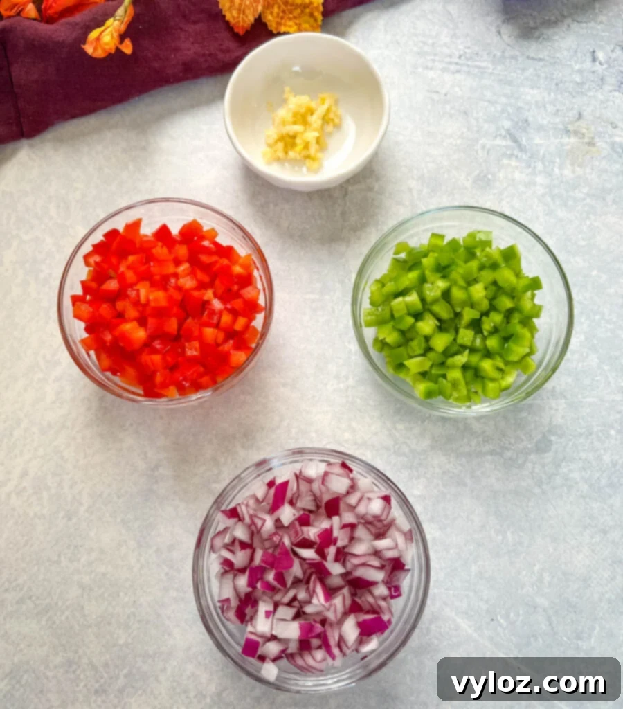 Hearty Ground Chicken Chili 3 Close-up of freshly chopped garlic, green bell peppers, red bell peppers, and red onions in separate glass bowls, ready for cooking.