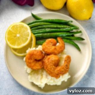 Delicious lemon pepper shrimp, mashed potatoes, and green beans on a plate, ready to be served.