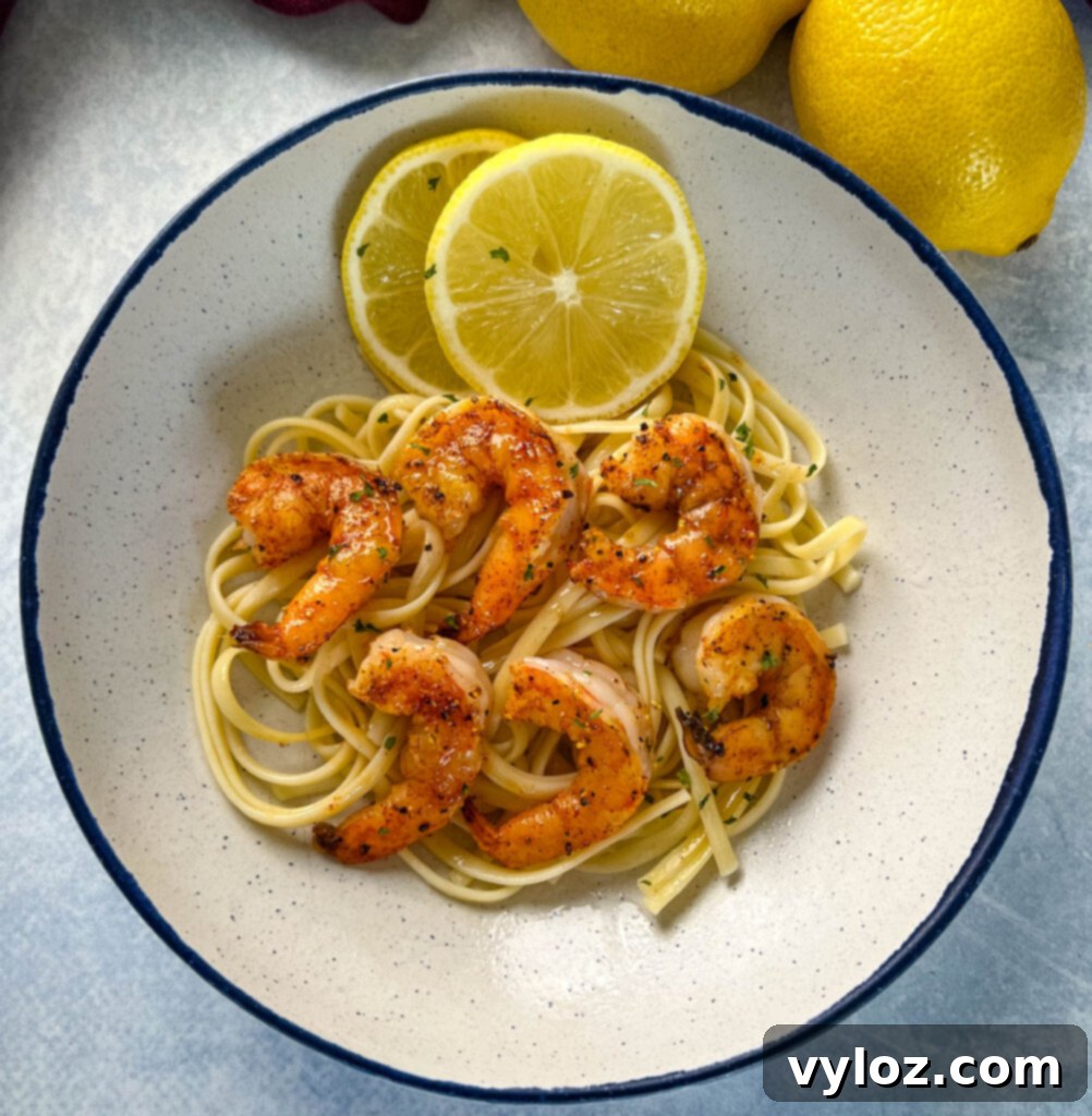 Perfectly cooked lemon pepper shrimp served over a bed of pasta, garnished with fresh parsley and lemon wedges, ready to be enjoyed.