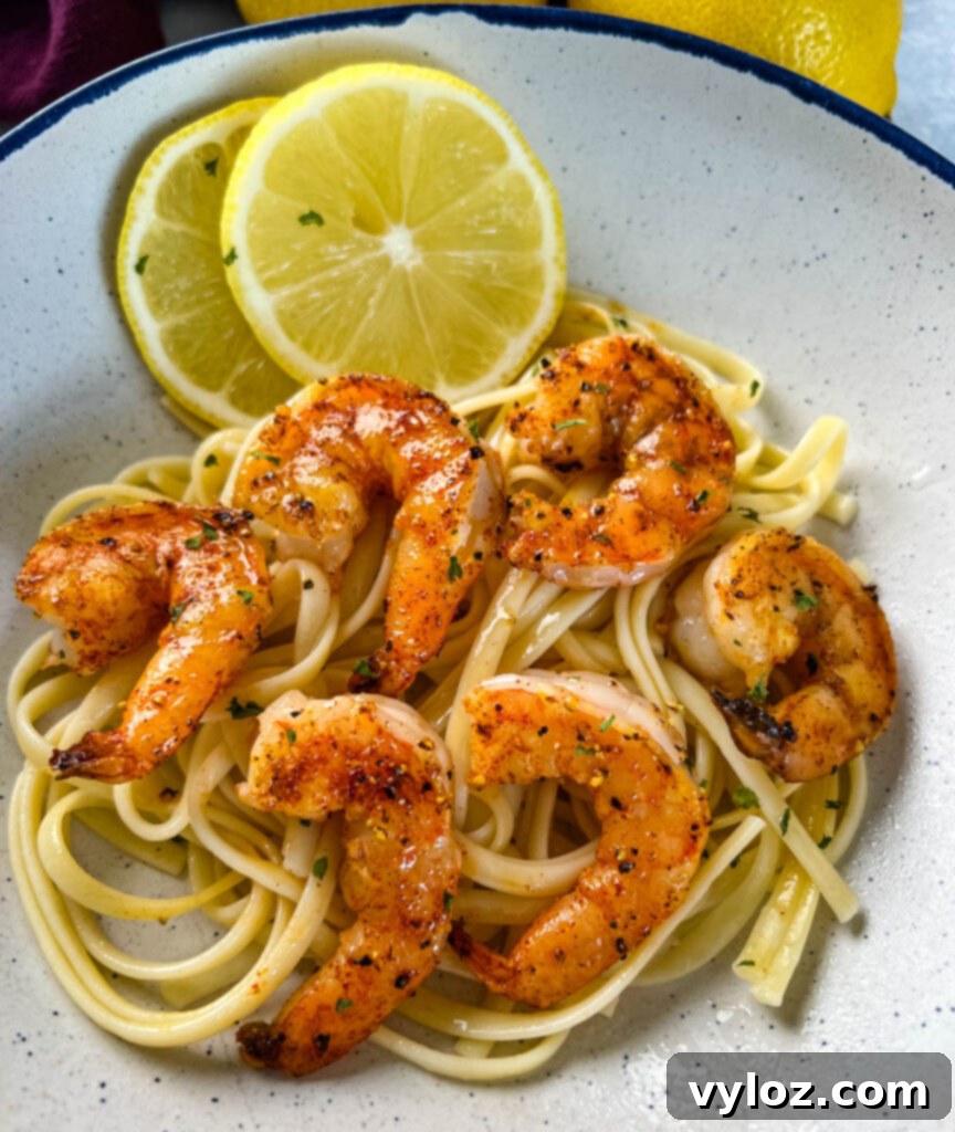 Another perspective of delicious lemon pepper shrimp served over pasta, showcasing the vibrant colors and appealing presentation.