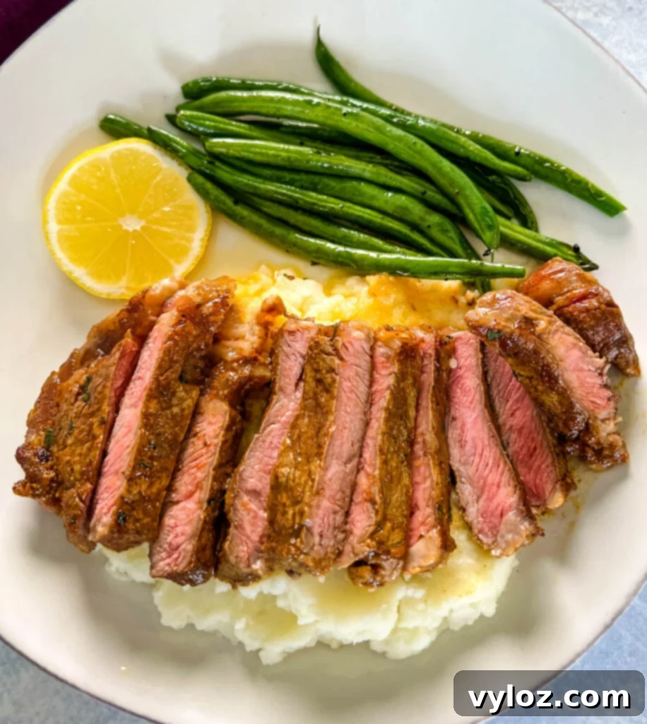 Zesty Lemon Pepper Steak 14 sliced lemon pepper steak with mashed potatoes and green beans on a white plate