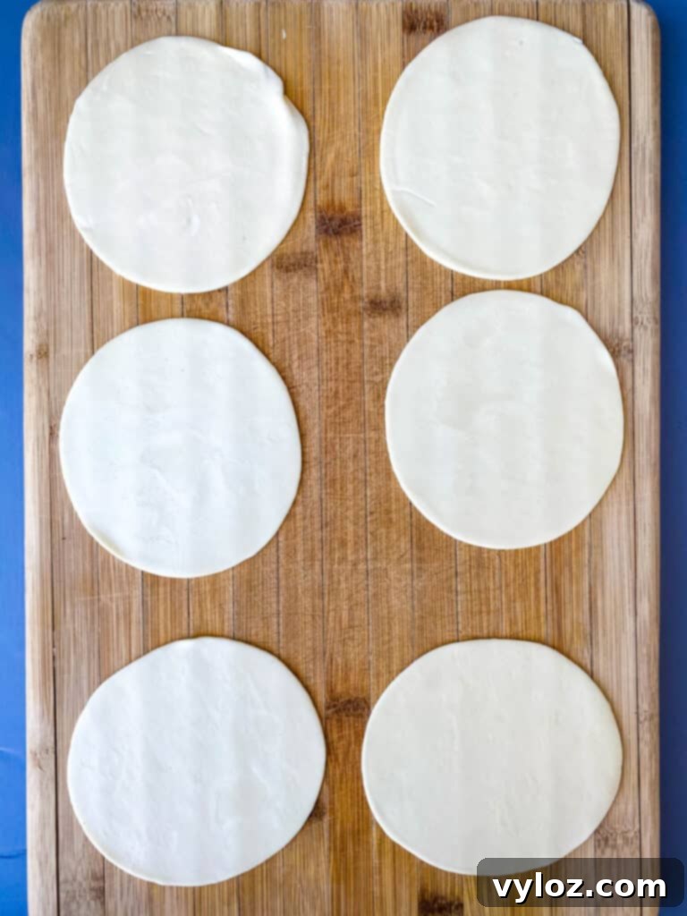 Empanada wrappers neatly laid out on a cutting board, prepared for filling and assembly.