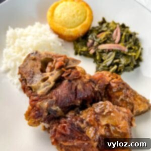 southern pork neck bones on a white plate with rice, collard greens, and cornbread