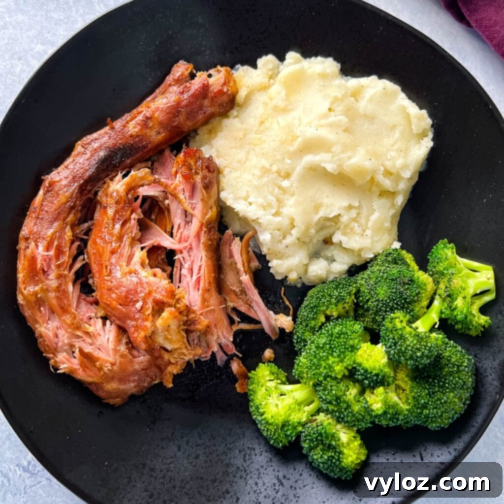 A black plate featuring richly smoked turkey necks, accompanied by creamy mashed potatoes and vibrant green broccoli.