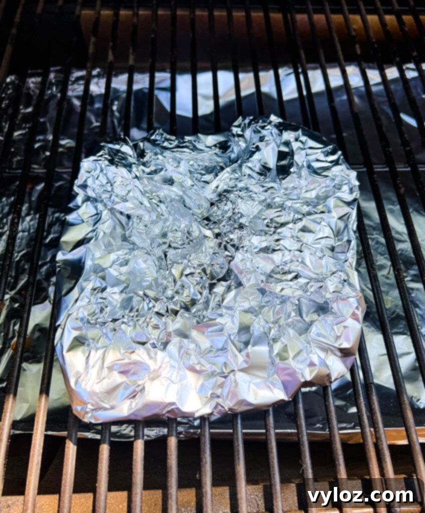 Smoked turkey necks, tightly wrapped in aluminum foil, are placed back on the smoker to continue cooking and tenderizing.