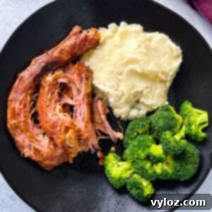 Richly smoked turkey necks, creamy mashed potatoes, and vibrant broccoli served on a sleek black plate.