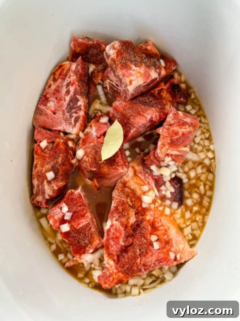 Pork neck bones, onions, and broth simmering in a slow cooker, creating a rich and aromatic stew
