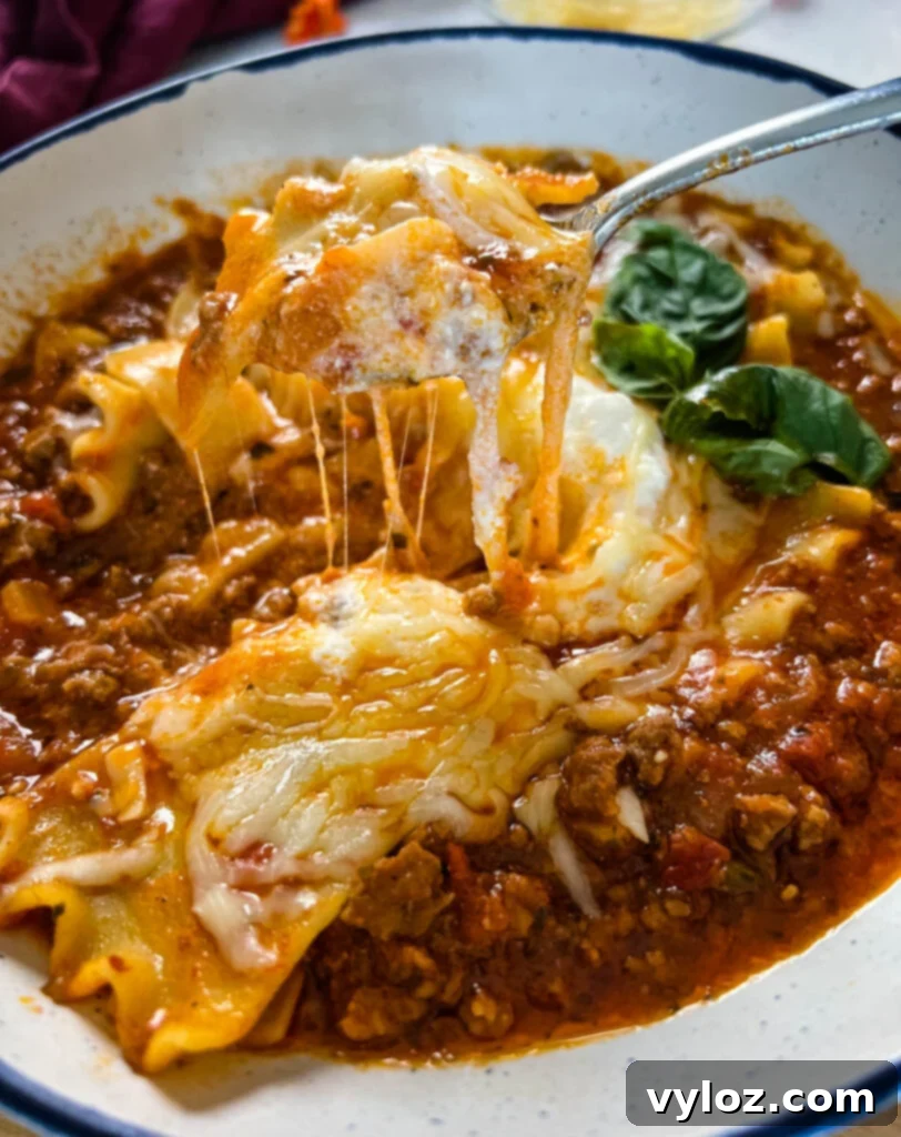 cheese pull of lasagna soup in a bowl, showcasing creamy texture and melted cheese