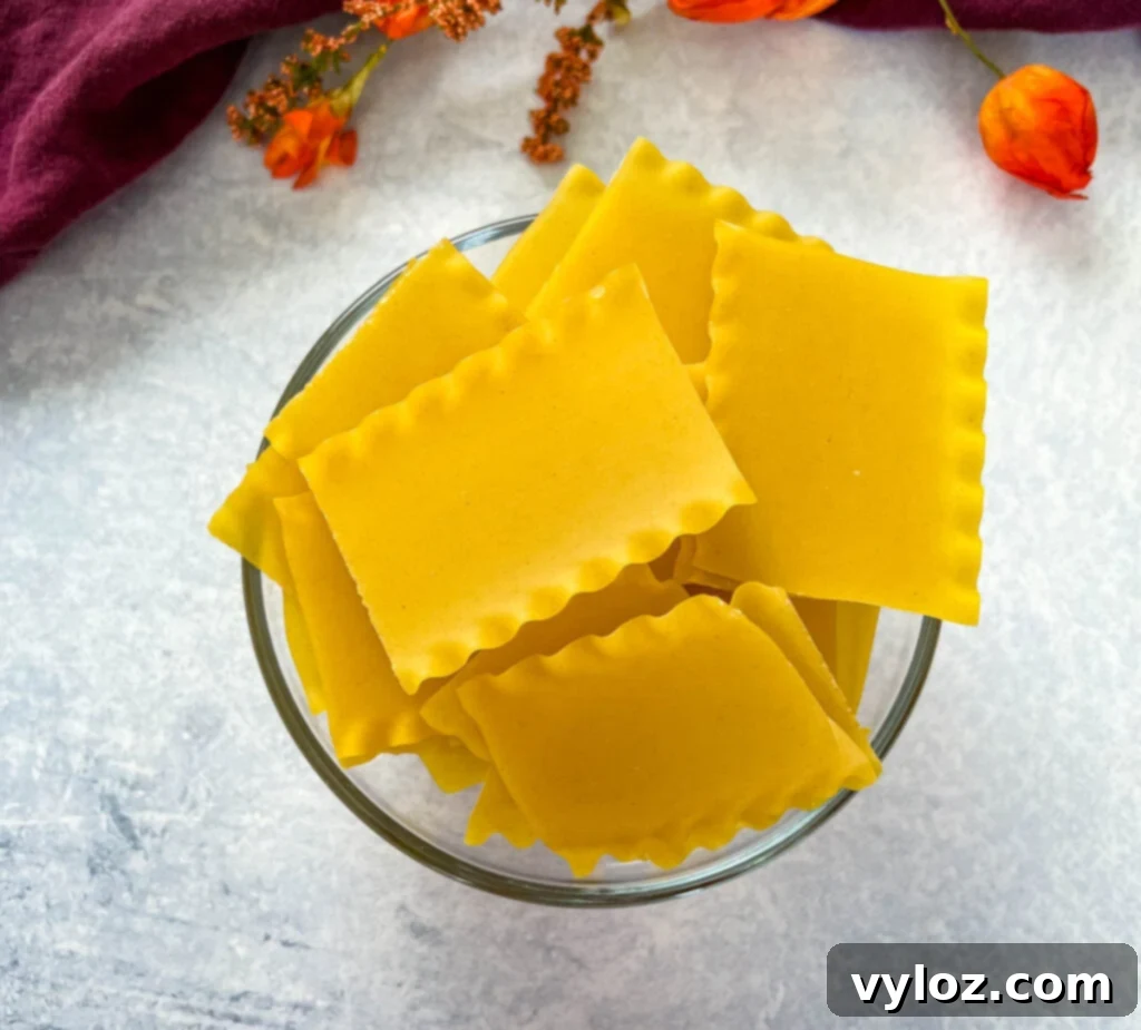 uncooked lasagna pasta in a glass bowl, broken into smaller pieces
