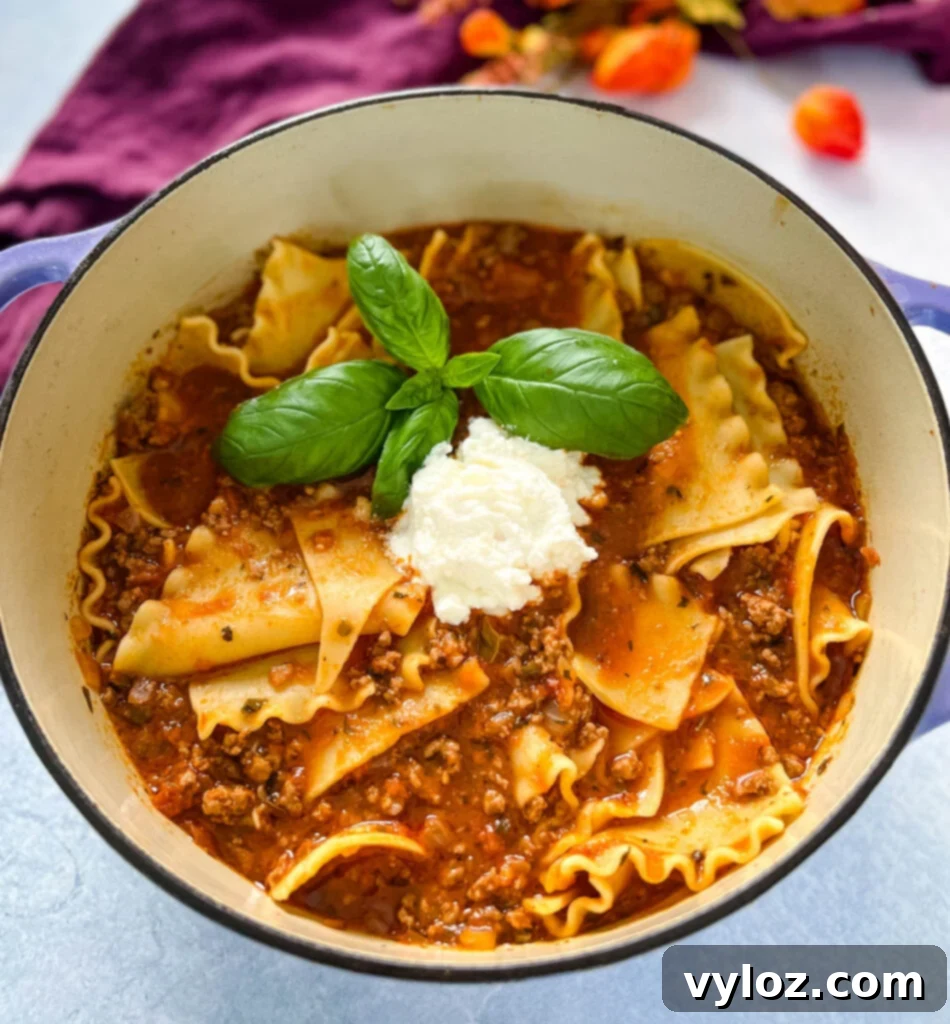 beef lasagna soup with basil and cheese in a large pot, ready to be served