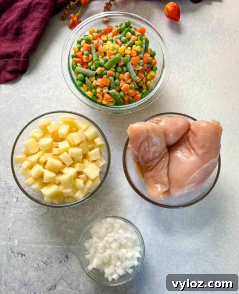 mixed vegetables, potatoes, raw chicken breasts, and chopped onions in separate glass bowls