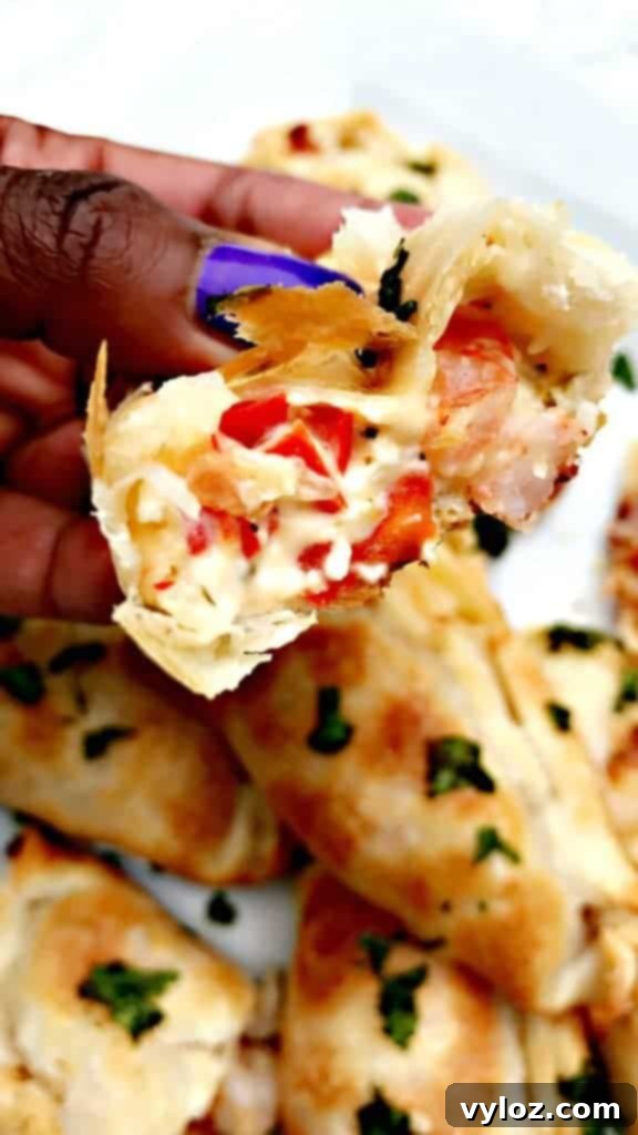 Savory Shrimp Red Pepper Cream Cheese Empanadas 8 A stack of golden, flaky Shrimp Red Pepper Cream Cheese Empanadas on a plate with a bite taken out, showing the creamy filling