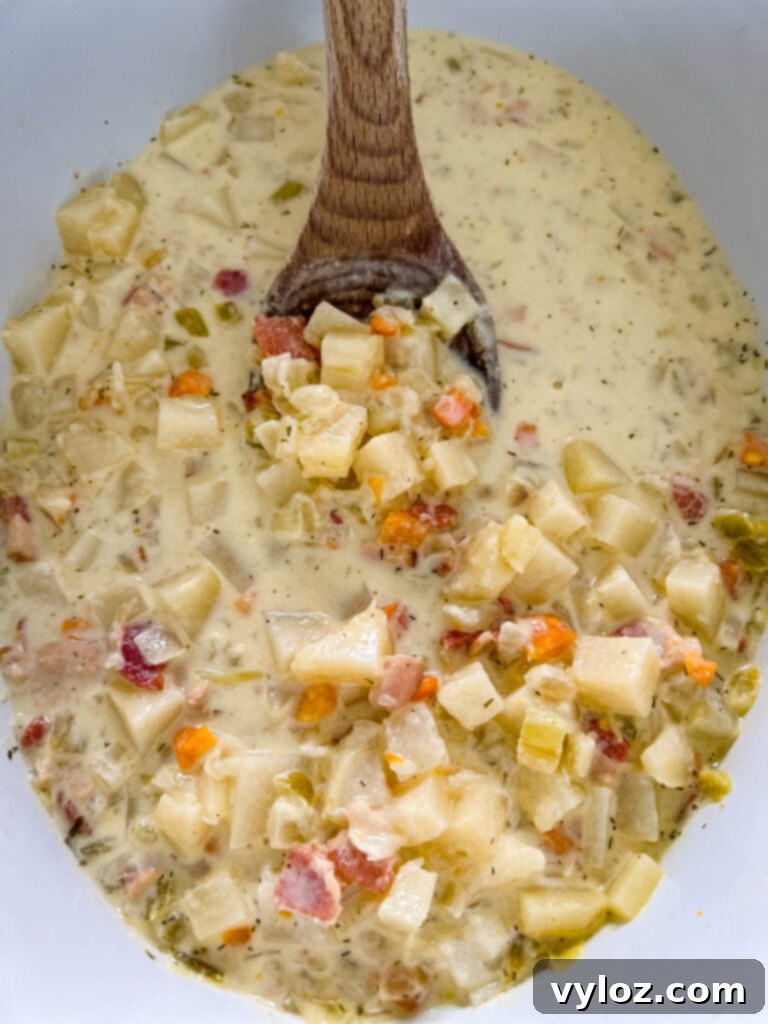 bacon potato soup in a pot with a wooden spoon