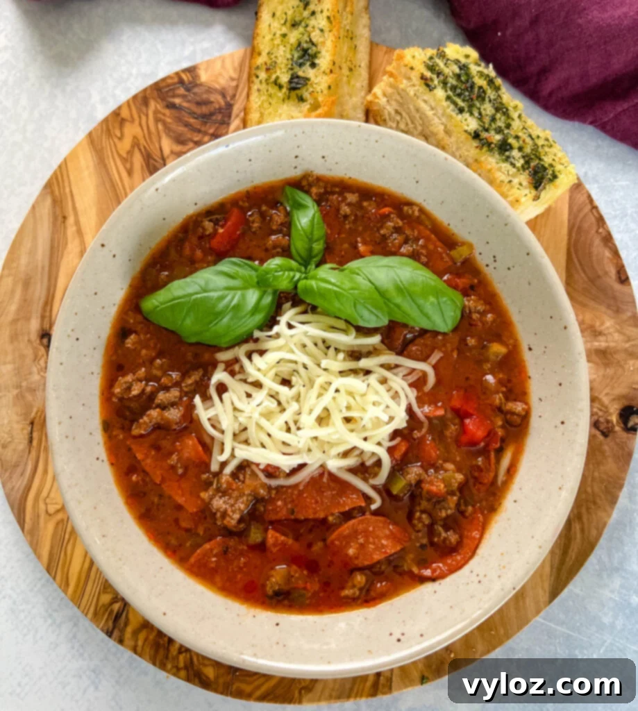 Hearty pizza soup with ground beef, vibrant pepperoni slices, melted mozzarella, and fresh basil in a rustic bowl