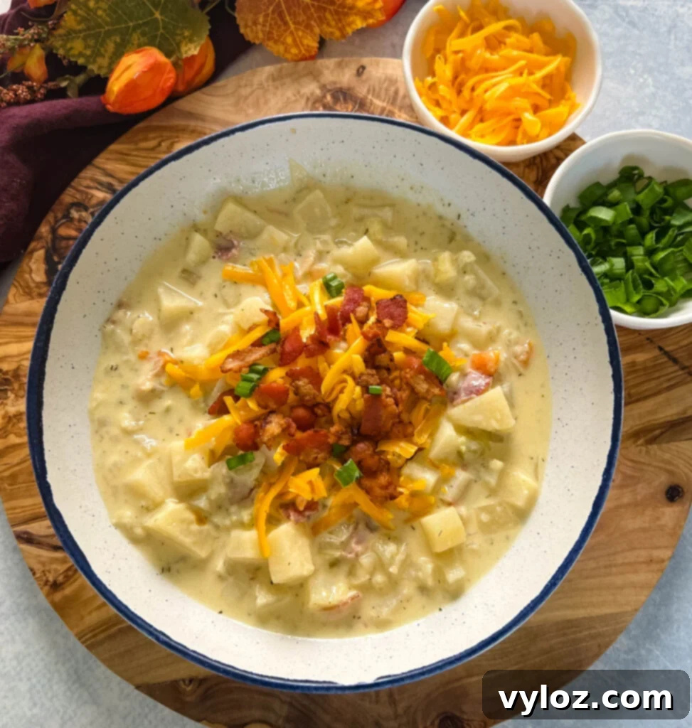 Ultimate Slow Cooker Loaded Potato and Bacon Soup 2 A bowl of creamy slow cooker loaded potato soup, garnished with crispy bacon and shredded cheese, ready to be enjoyed.