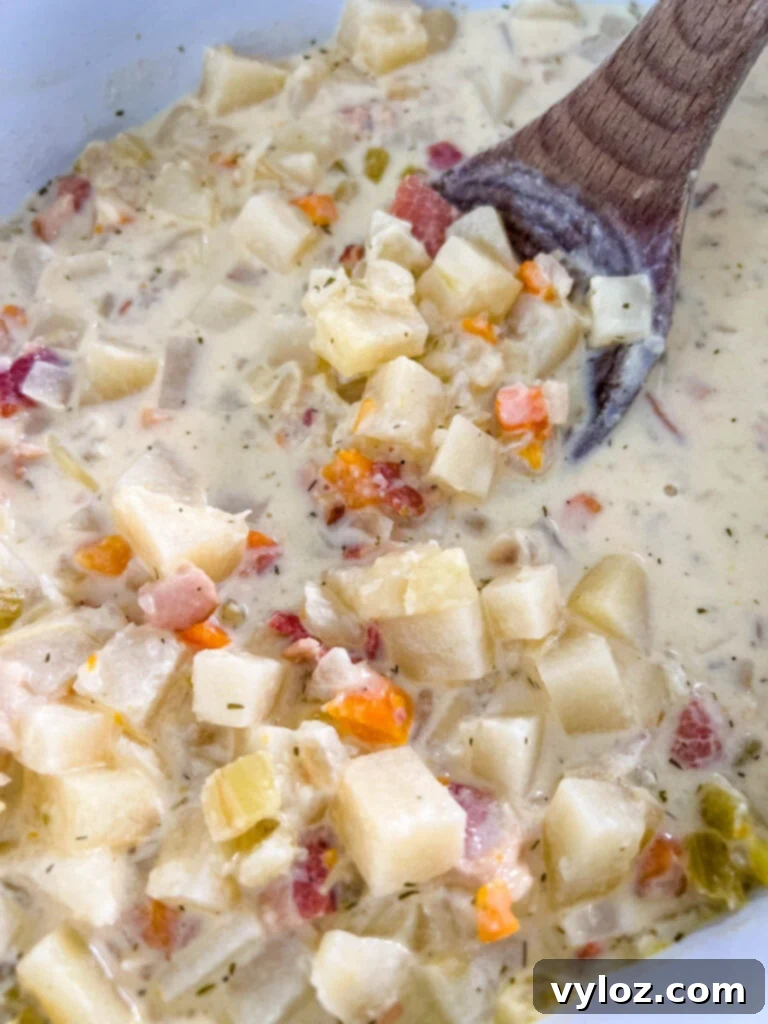 Ultimate Slow Cooker Loaded Potato and Bacon Soup 11 A slow cooker filled with creamy, loaded potato soup, garnished with herbs and ready to be served, highlighting its rich texture.