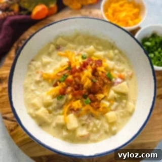 Ultimate Slow Cooker Loaded Potato and Bacon Soup 12 A pristine white bowl showcasing the creamy slow cooker loaded potato soup, artfully garnished with crispy bacon and shredded cheese.