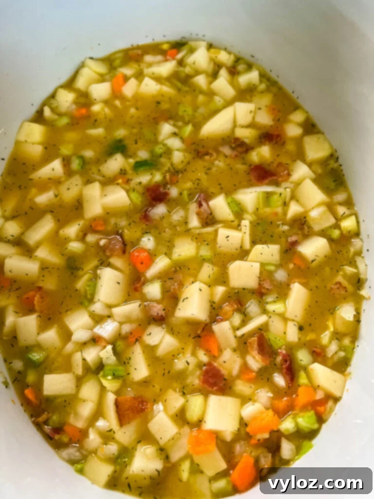 Ultimate Slow Cooker Loaded Potato and Bacon Soup 6 Rich, creamy loaded potato soup simmering gently in a Crockpot slow cooker, emitting a comforting warmth.