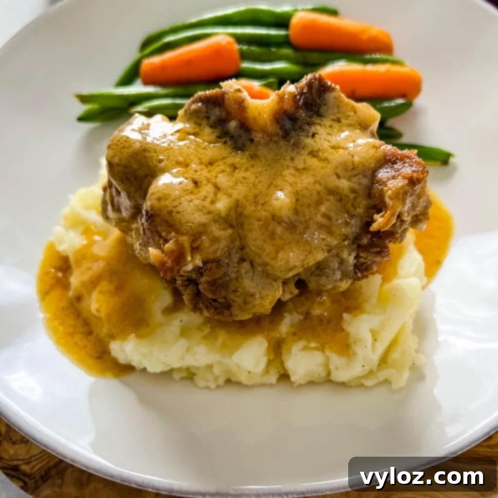slow cooker crockpot oxtails with mashed potatoes, gravy, green beans, and carrots on a plate