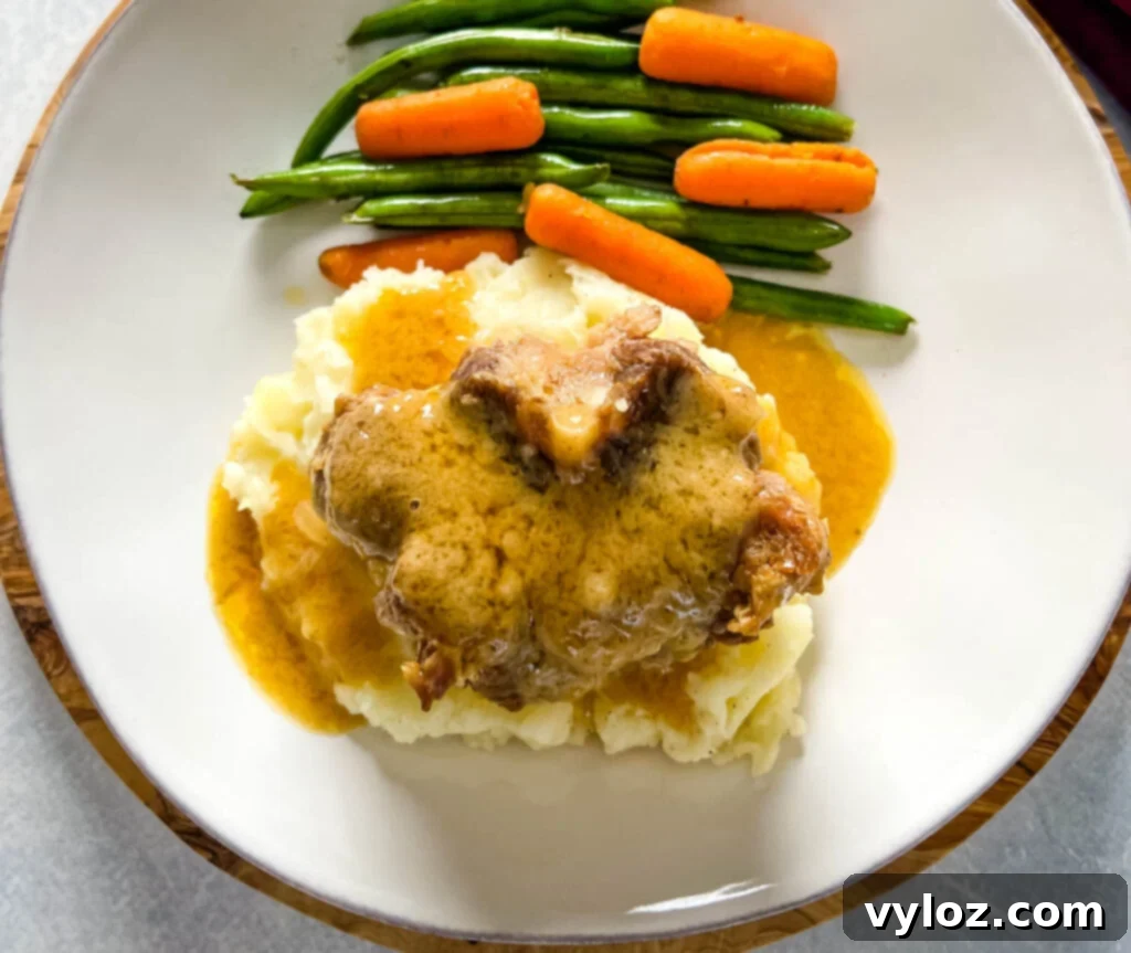 slow cooker crockpot oxtails with mashed potatoes, gravy, green beans, and carrots on a plate